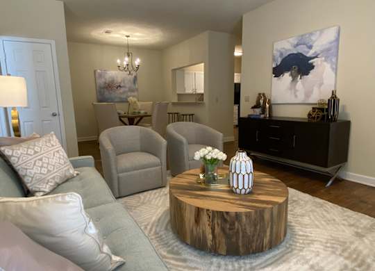 A living room with a grey couch, a wooden coffee table, and a painting on the wall.