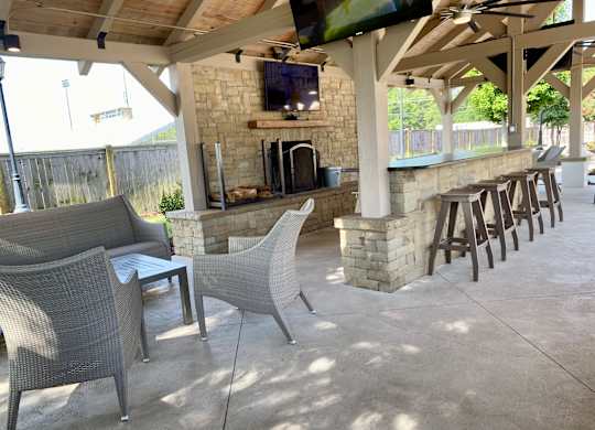 A patio with a stone fireplace and chairs.