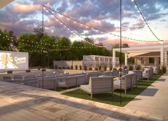a patio with seating and a movie screen at dusk at The Azul Apartment Homes in Oxford, 38655