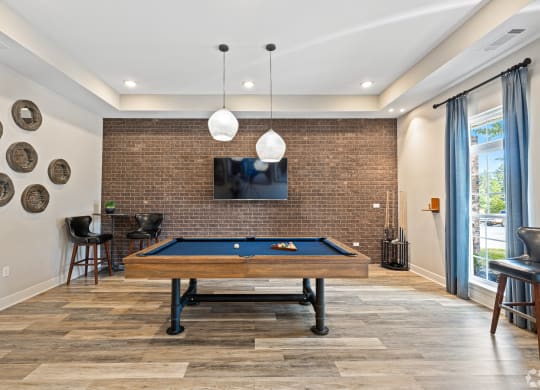 a living room with a pool table and a wall mounted tv at The Met Apartment Homes, Hattiesburg, 39402