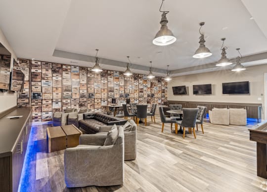 a lounge area with couches chairs and tables and a bar at The Met Apartment Homes, Hattiesburg