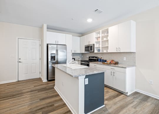 a kitchen with white cabinets and a stainless steel refrigerator at The Met Apartment Homes, Hattiesburg, Mississippi