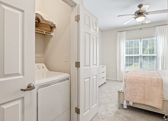 a laundry room with a closet and a bed and a ceiling fan at The Met Apartment Homes, Hattiesburg, MS