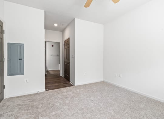 an empty living room with white walls and a door to a hallway at The Met Apartment Homes, Mississippi