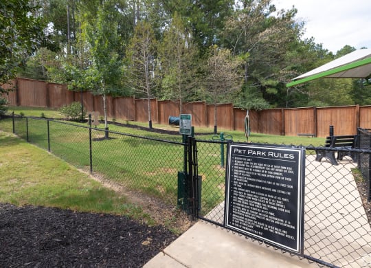 a dog park with a sign on a chain link fence at The Met Apartment Homes, Hattiesburg