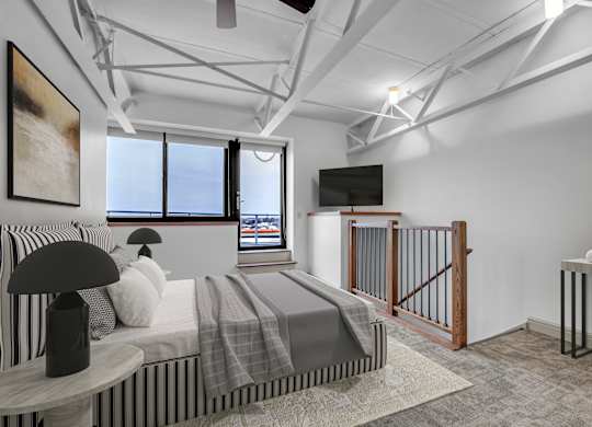 A modern bedroom with a large bed and a television. at 100 South Apartments, Buffalo, NY
