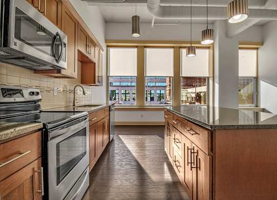 A kitchen with wooden cabinets and a marble countertop. at 100 South Apartments, Buffalo