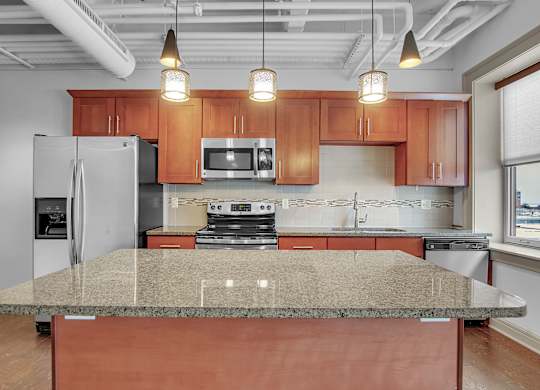 A kitchen with a granite countertop and wooden cabinets. at 100 South Apartments, Buffalo, New York