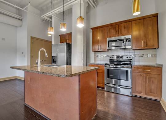 an empty kitchen with a granite counter top and stainless steel appliances at 100 South Apartments, Buffalo, 14202