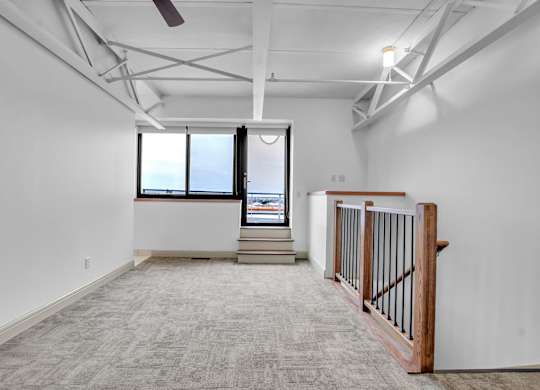 A spacious room with a large window and a ceiling fan at 100 South Apartments, Buffalo