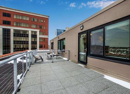 A rooftop patio with a table and chairs overlooking a cityscape at 100 South Apartments, Buffalo, New York