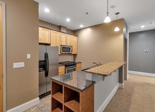 Modern kitchen with peninsula counter and bar seating at The Granite Works Apartments, Buffalo, 14202