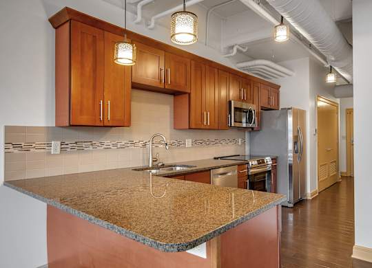 Kitchen with island granite countertops and pendant lighting at 100 South Apartments, New York, 14202
