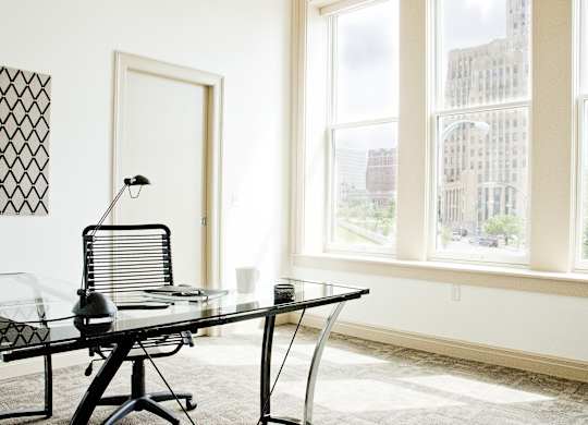 a glass desk in a room with three windows at 100 South Apartments, Buffalo, NY 14202