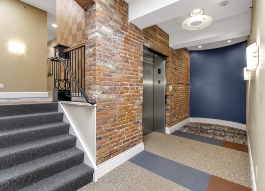 the front door of a building with a brick wall and stairs at The Granite Works Apartments , Buffalo, NY