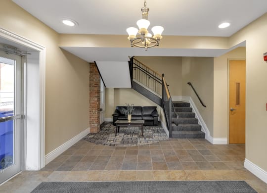 a lobby with a staircase and a couch and a chandelier at The Granite Works Apartments , New York 14202