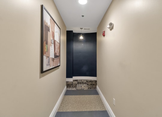 a long hallway with a black accent wall and carpeted flooring and a staircase at The Granite Works Apartments , Buffalo, New York