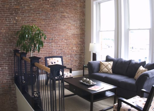 a living room with a brick wall and a couch and a table at The Granite Works Apartments , Buffalo, NY, 14202