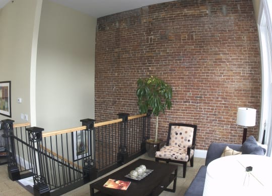 a living room with a brick wall and a couch and a chair at The Granite Works Apartments , New York 14202