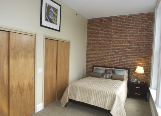 a bedroom with a bed and a brick wall at The Granite Works Apartments , New York