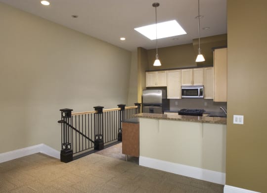 an empty living room with a staircase and a kitchen at The Granite Works Apartments , Buffalo, NY, 14202