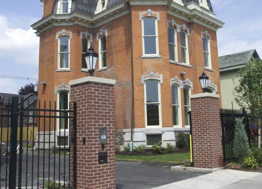 a red brick house with a black wrought iron gate at The Granite Works Apartments , Buffalo