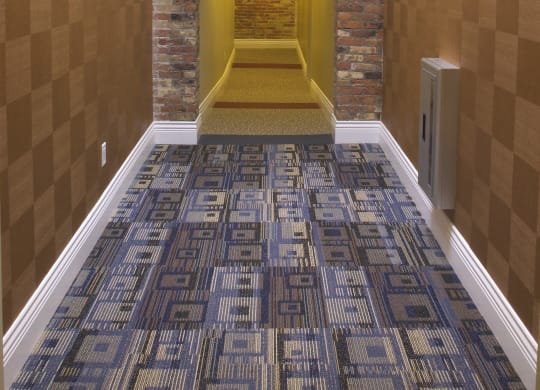 a hallway with a carpeted floor and a brick wall with a ceiling light at The Granite Works Apartments , Buffalo, New York
