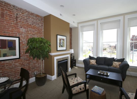 a living room with a brick wall and a couch and a table at The Granite Works Apartments , Buffalo, NY, 14202