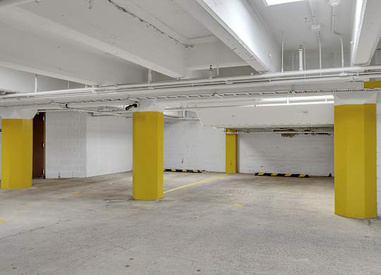 a parking garage with white walls and yellow pillars at 100 South Apartments, Buffalo, New York