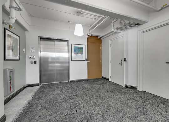 a room with a carpeted floor and a hallway with doors at 100 South Apartments, New York, 14202