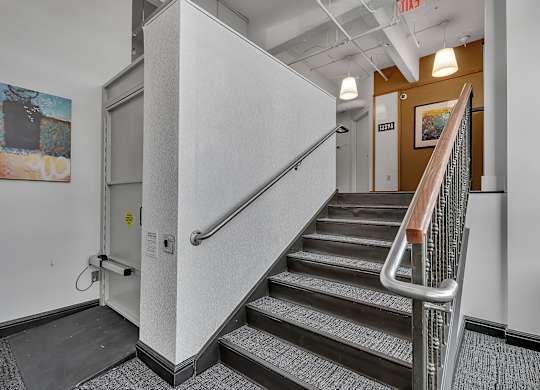 a stairwell in a building with stairs and a railing and a door at 100 South Apartments, Buffalo, NY 14202