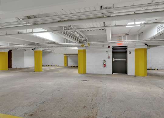 a parking garage with yellow pillars and a door at 100 South Apartments, Buffalo, 14202