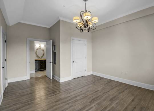 an empty living room with wood floors and a chandelier at The Knights @ 506 Delaware Apartments, Buffalo, 14202