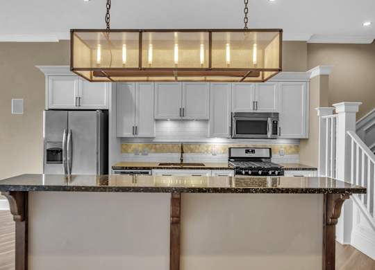 a kitchen with an island with a granite counter top and white cabinets at The Knights @ 506 Delaware Apartments, Buffalo, NY 14202