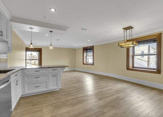 an open kitchen and living room with white cabinets and wood floors at The Knights @ 506 Delaware Apartments, New York, 14202
