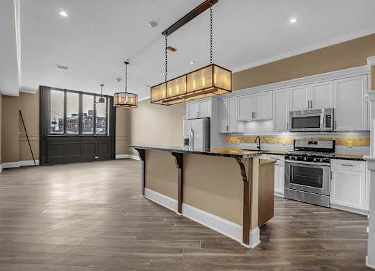 A modern kitchen with a dark wood floor and white cabinets at The Knights @ 506 Delaware Apartments, Buffalo, 14202