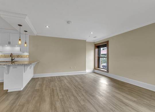 an empty living room with a kitchen and a window at The Knights @ 506 Delaware Apartments, Buffalo