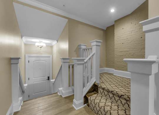 A staircase with a white railing and a brown carpeted stairway at The Knights @ 506 Delaware Apartments, Buffalo, New York