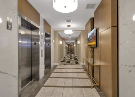 a long hallway with elevators and marble floors at Nineteen North, New York, 14202