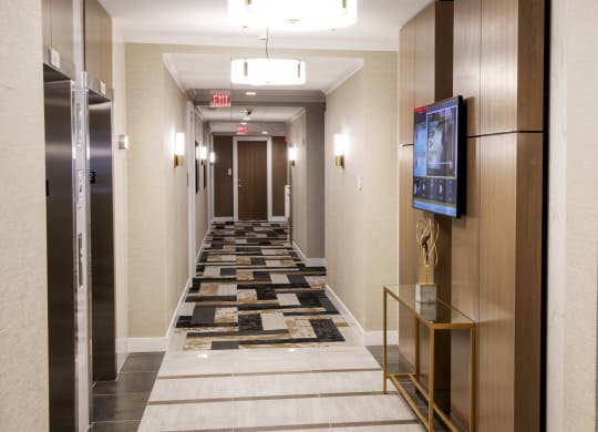 a long corridor with elevators and a carpeted hallway with a tv and elev at Nineteen North, New York