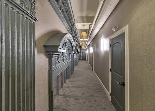 a long hallway with a door and columns on the side at The Knights @ 506 Delaware Apartments, New York, 14202