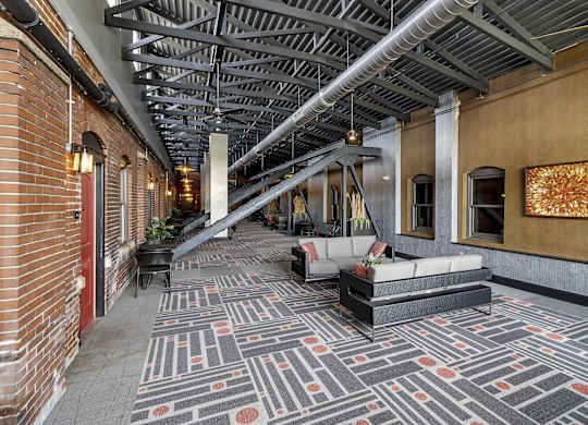 the lobby of a building with couches and a rug at The Knights @ 506 Delaware Apartments, Buffalo, NY 14202
