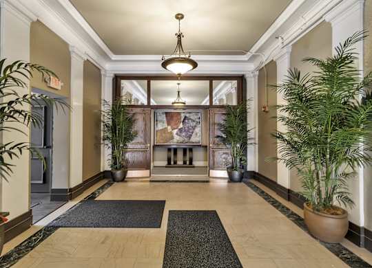 a lobby with potted plants and a large glass door at The Knights @ 506 Delaware Apartments, Buffalo, New York