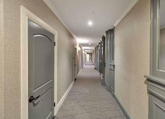 a hallway with blue doors and white walls and a tiled floor at The Knights @ 506 Delaware Apartments, Buffalo, 14202