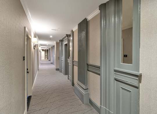a long hallway with gray doors and white walls at The Knights @ 506 Delaware Apartments, Buffalo, New York
