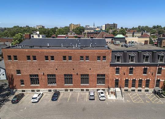 an aerial view of a brick building with cars parked in front of it at The Knights @ 506 Delaware Apartments, Buffalo, 14202