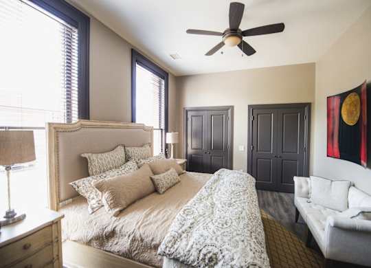 a bedroom with a large bed and a ceiling fan at The Knights @ 506 Delaware Apartments, Buffalo, 14202