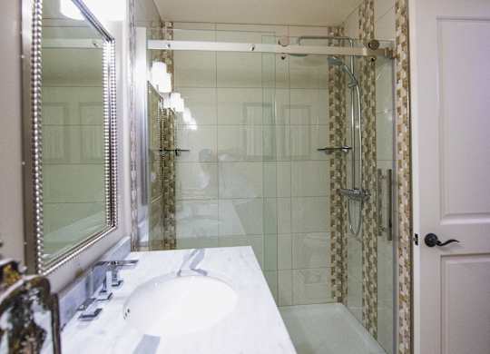 a bathroom with a shower and a sink and a mirror at The Knights @ 506 Delaware Apartments, New York, 14202