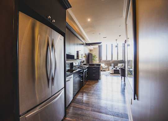a large kitchen with stainless steel appliances and a wooden floor at The Knights @ 506 Delaware Apartments, Buffalo, 14202
