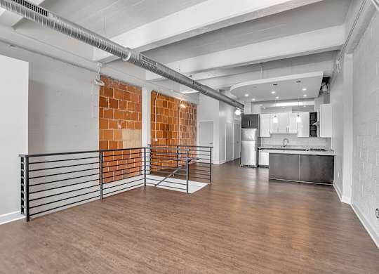 Loft living area with exposed brick and modern kitchen at The Lofts at Elk Terminal Apartments, Buffalo, NY